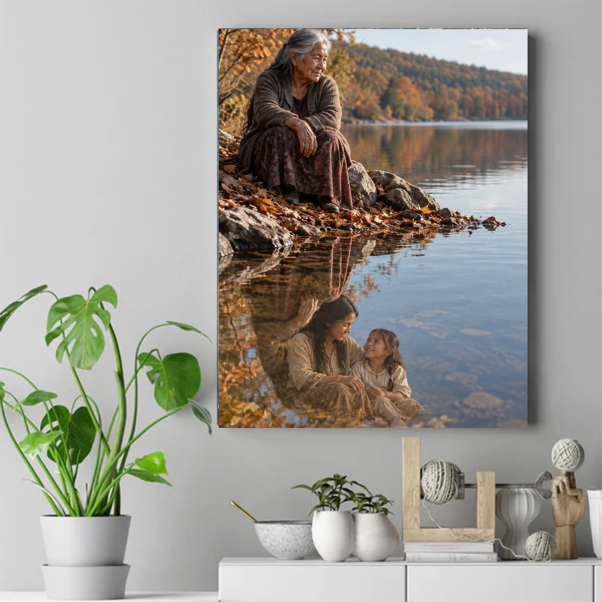 Older Native woman sitting on rocks by an autumn lake, her reflection showing a younger woman and a little girl – ảnh 2