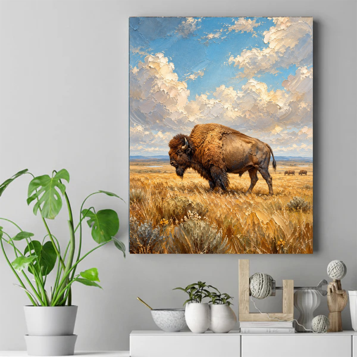A bison walking through tall golden grass under a blue sky with large white clouds and two distant bison. – ảnh 2