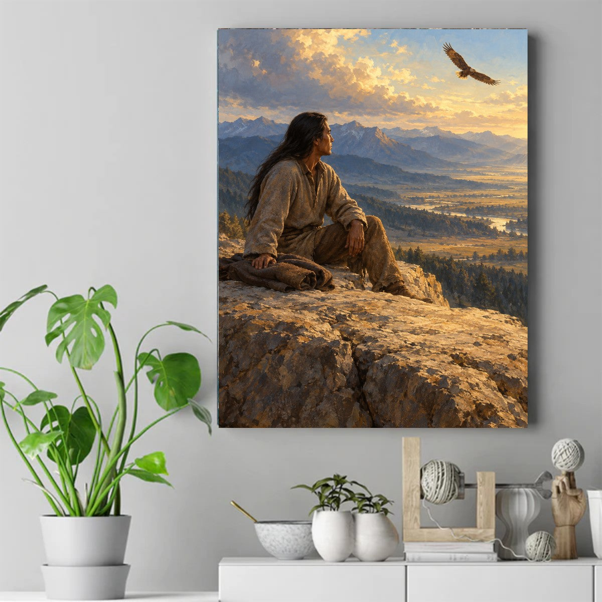 Native American man seated on rock looking up at eagle flying in golden sunset sky with mountains and valley. – ảnh 2