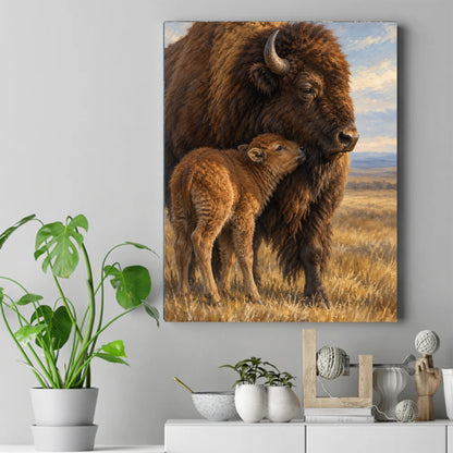 Large brown bison standing in golden grass with a small light brown calf nuzzling against its chest under a blue sky – ảnh 2