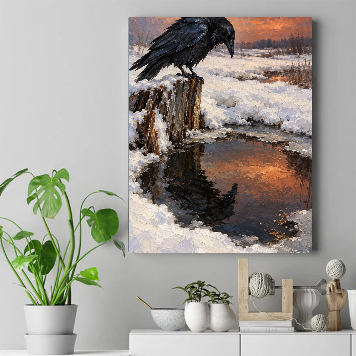 A black raven perched on a snowy wooden stump, looking down at dark water that reflects an orange sunset sky. – ảnh 2