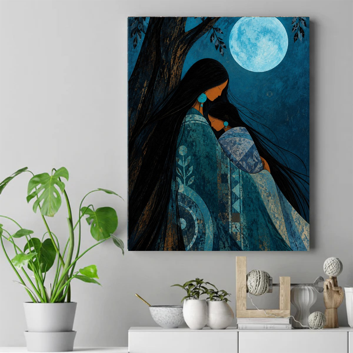 Native mother with long black hair holding her child close under a full moon, wearing blue and teal patterned blankets. – ảnh 2
